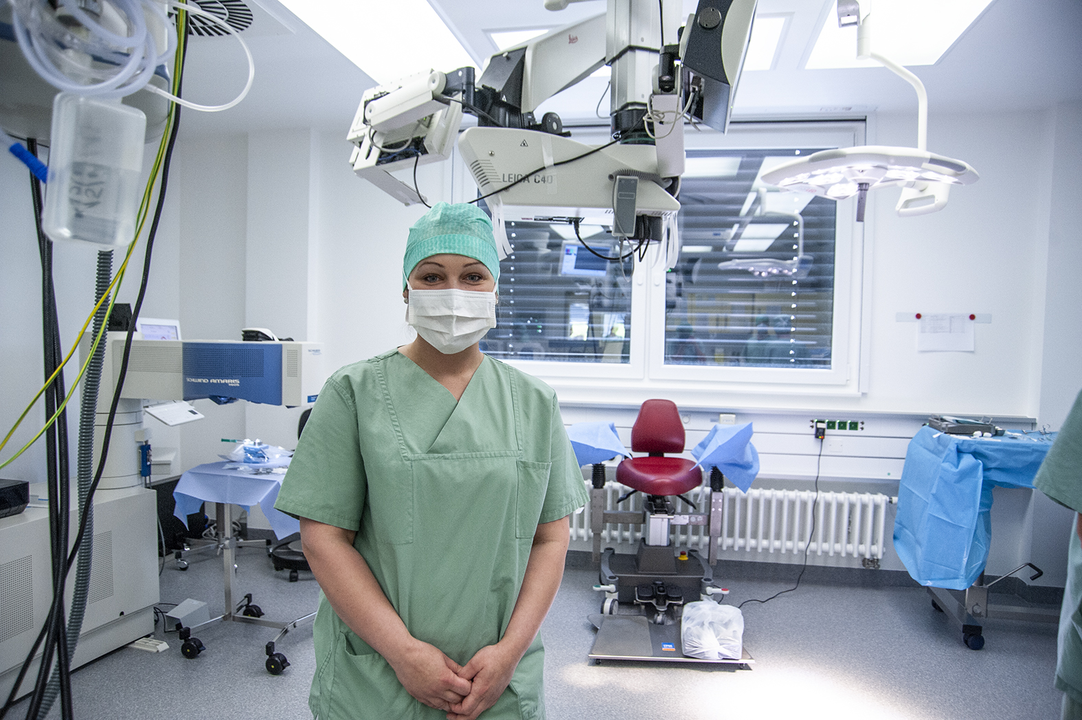 View into an operating room for eye surgery. In the foreground is a surgical assistant.